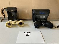 Both the opera glasses and Bushnell binoculars with their respective cases placed side by side on a table.