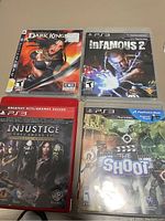 Photo showing 4 PS3 game cases: Dark Kingdom, Infamous 2, Injustice: Gods Among Us, The Shoot with visible cover art and labels.