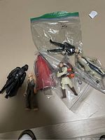 Photo of six Star Wars action figures mostly from the 1990s on a flat surface, some loose and some inside plastic bags.
