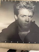 Front cover of Bryan Adams Reckless vinyl album showing close-up black and white portrait of Bryan Adams with album title and artist name visible.