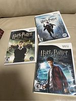 Photo showing three Harry Potter video game cases for Nintendo Wii on a beige couch.