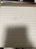Close-up of the album cover showing the white brick wall design with some stains and discoloration marks.
