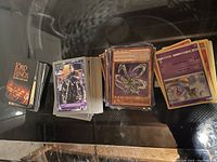Photo showing stacks of trading cards on a glass surface, including Yu-Gi-Oh!, Terminator 2, Lord of the Rings, and Pokémon cards.