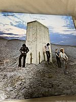 Vinyl album cover showing the band The Who standing around a concrete pillar on a rocky landscape under a cloudy blue sky.