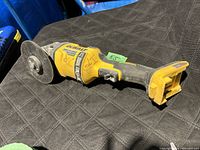 Side view showing the yellow and black DeWalt cordless angle grinder with visible dirt and missing battery.