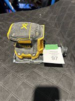 Yellow and black DeWalt XR cordless palm sander placed on a dark surface, missing battery, showing dust and usage marks.