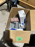 Box with various electrical components including outlets and switches in packaging.