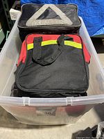 Photo of two roadside safety kits in a clear plastic bin, black with reflective triangle and black/red with yellow strip