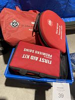 Photo of three red first aid kits/fabric pouches, including one from St. John Ambulance, one round Promedics kit, and a rectangular kit.
