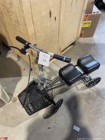 Three-quarter side view of the knee scooter showing the seat cushions, basket, and wheels.