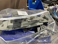 Clear plastic bag containing a partially built Lego gray military ship model with 'U-159' markings and some loose Lego bricks inside.