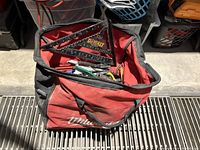 Photo of red Milwaukee tool bag partially filled with tools, showing DeWalt combination squares on top.