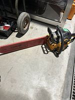 Full view of Poulan Pro gas chainsaw with red Jonsered bar cover on concrete floor showing overall item.
