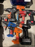 Top view of the eight assorted cordless power tools laid out showing model variety and color.