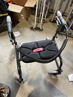 Top-down view of the rollator walker showing the padded seat, folding metal frame, and ergonomic handles with brakes.