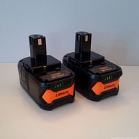 Two black and orange Vanon 18V Lithium batteries with LED charge indicators shown upright against white background.