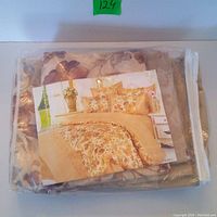 Bedding set in clear plastic packaging displaying the floral bedding pattern on a cardboard insert showing the set on a bed.