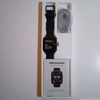 Photo showing MILOUZ IDW26 smart watch in original packaging with watch, charger, and operation manual