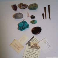 12 piece lot including 8 natural semi-precious stones, crystals and minerals, with 3 antique steel nails, all laid out with several identification tags visible.