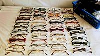Photo showing 45 pairs of prescription glasses, arranged in rows, showcasing a variety of frame shapes, colors, and materials