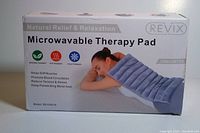 Box front showing the product name 'Microwavable Therapy Pad' by REVIX with an image of a woman using the heating pad on her back, and claims of natural relief and relaxation benefits.