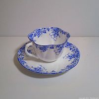 Side view of Shelley fine bone china tea cup with matching saucer, showing floral pattern and scalloped edges