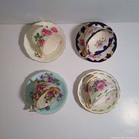 Top view of four floral teacups with five saucers, showing designs and condition.
