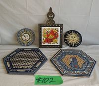Full view of the lot showing cast iron trivet with ceramic tile, two round sun decorations, and two hexagonal Semigres tiles