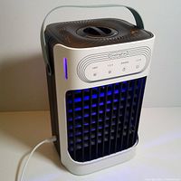 Side angled view of the portable air conditioner plugged in and powered on with visible blue LED light and control panel showing various function buttons.