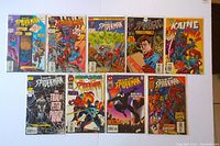 Lot of 9 Web of Spider-Man comic books laid out showing front covers, featuring characters like Scarlet Spider, Kaine, and Peter Parker. Comics appear in protective sleeves with backboards.
