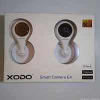 Front view of sealed box showing two XODO E4 cameras visible through window, Full HD 1080 and 2 Pack labels.