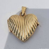 Front view of 14k gold heart locket showing ribbed gold design and clasp.