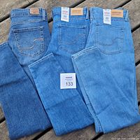 Three pairs of Levi's jeans folded showing back pockets and leather brand patches with two pairs new with tags