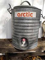 Front view of galvanized steel water cooler showing the 'arctic' decal and dispenser spout at bottom.