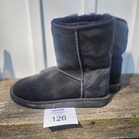 Side view of the left black shearling boot showing suede-like exterior and sole.
