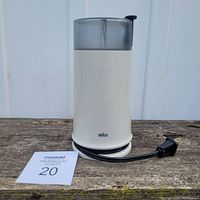 Front view of vintage Braun coffee grinder with cord wrapped around the base, showing clear lid and white body.