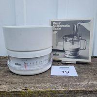 Front view of Braun kitchen scale with measuring bowl placed next to original box showing product image and branding.