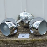 Front view showing two chrome eyeball lamp heads with bulbs inside, round chrome base with wiring.