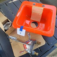Orange acrylic bar sink with two faucet holes and cutout for drain, also showing original care use label inside basin and original template underneath