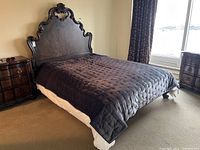 The entire bed setup including the wooden queen headboard with side rails, cabriole legs, and a dark comforter on mattress.