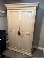 Full view of the closed cream painted wood wardrobe with detailed crown molding and base