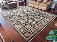 Full view of rectangular black area rug placed on hardwood floor among furniture