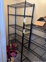 Photo showing full view of tall black metal shelving unit with six wire shelves in a corner.