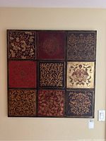 Full front view of the carved painted wall art showing nine detailed carved floral and ornamental panels in rich colors arranged in a grid.