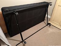 Black metal tubular foldable twin bed frame with caster wheels