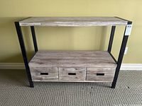 Front view of the console table showing the three drawers and metal frame.