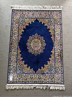 Full front view of the Persian style blue carpet rug laid flat, showing overall design and white fringe edges.