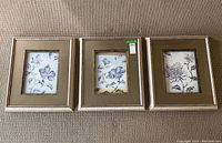 Set of three framed black and white floral prints laid side by side showing overall condition and style