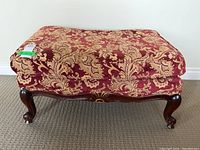 Full view of rectangular footstool showcasing wood cabriole legs and red chenille upholstery with gold floral pattern.