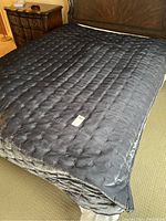 Grey quilted velvet blanket spread out on a bed showing full size and texture.
